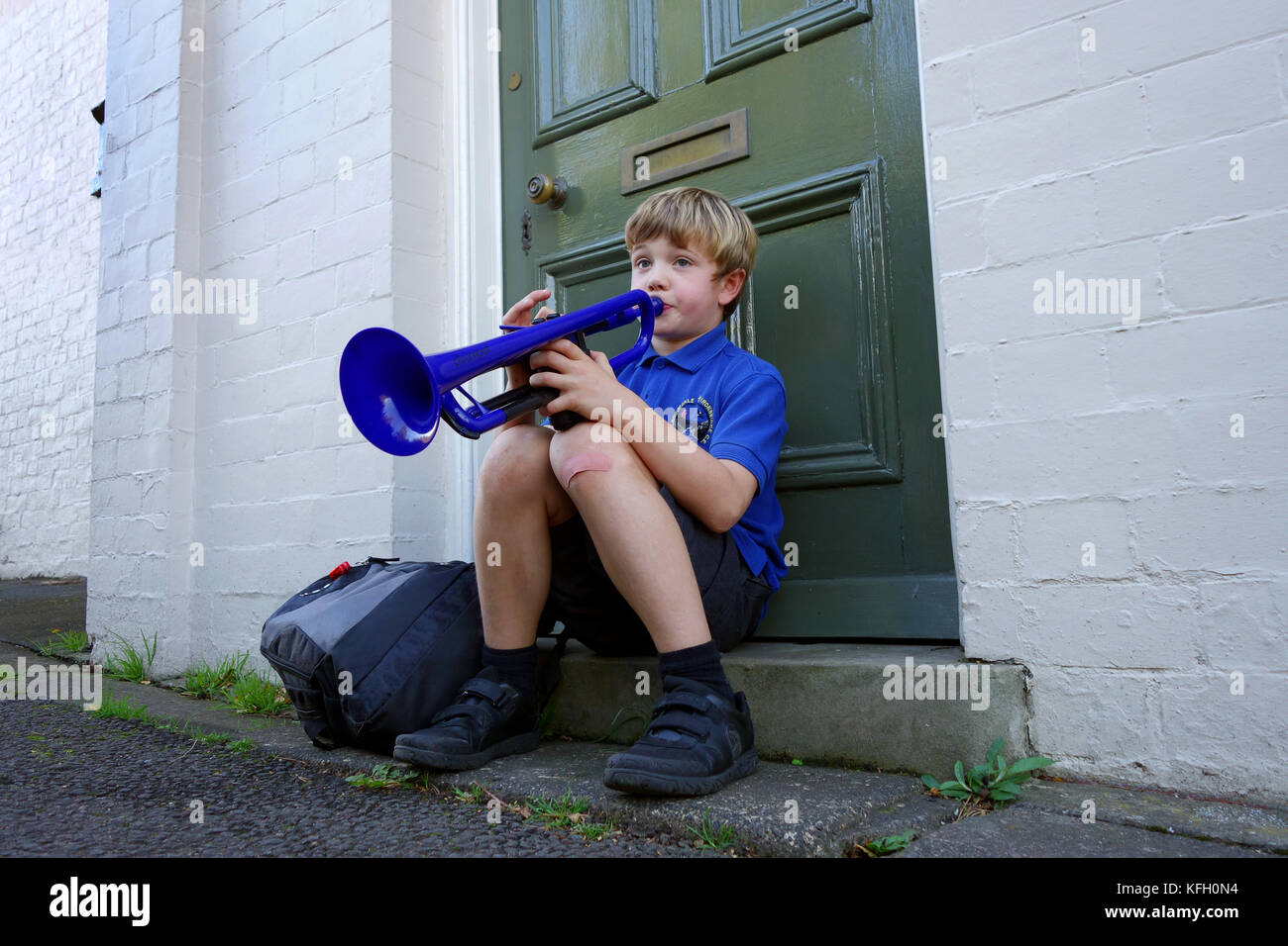 Music practice school boy playing trumpet on the doorstep Uk Stock Photo
