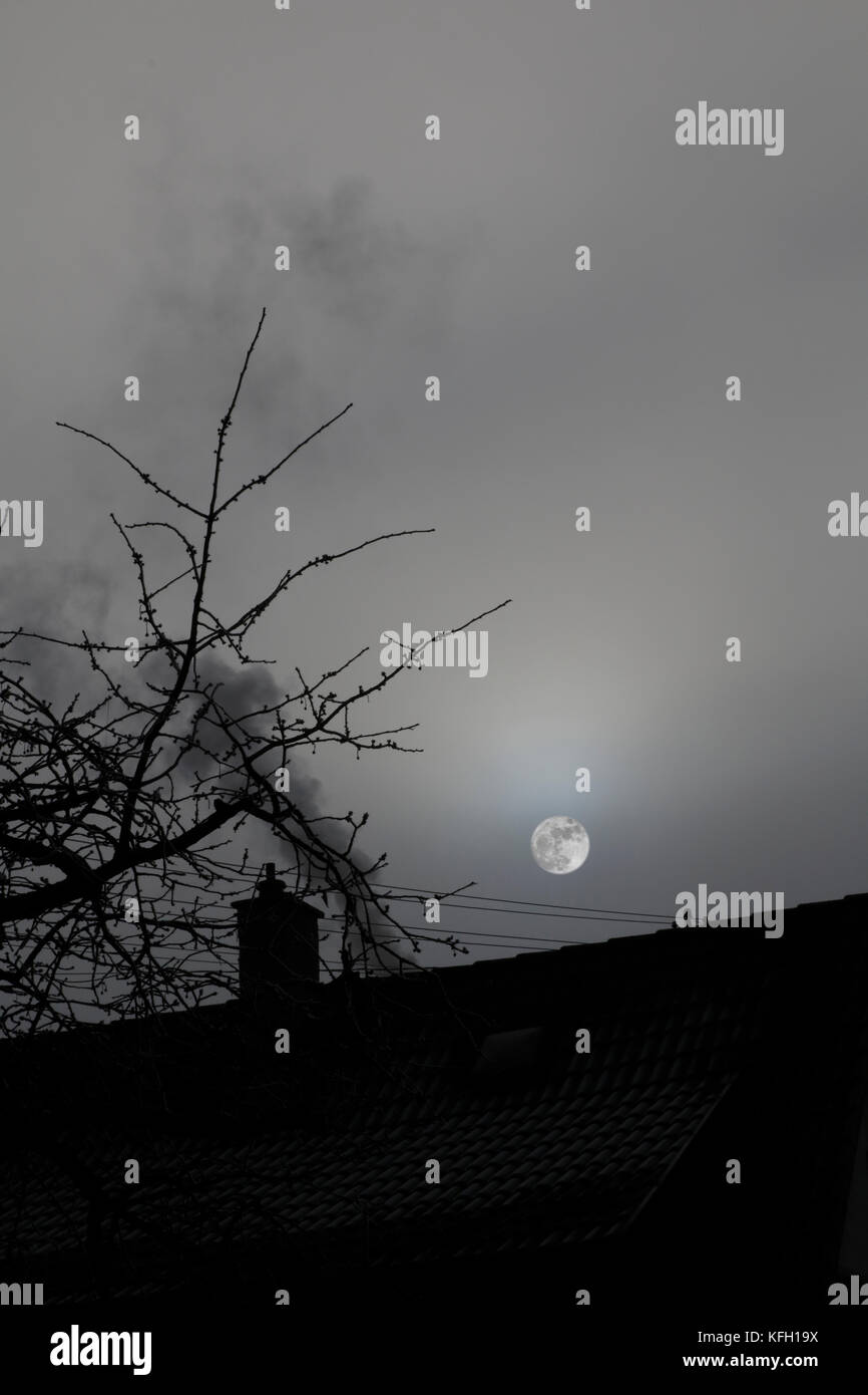 Dach mit Kamin, Rauch und dem Mond in mystischer Stimmung Stock Photo