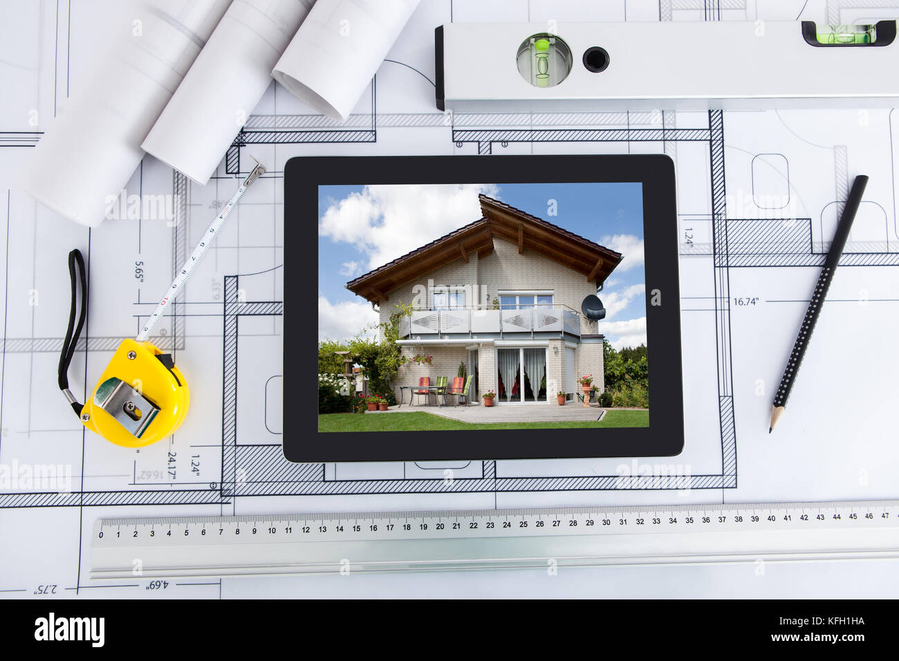 House displayed on digital tablet screen with architect's tools over ...