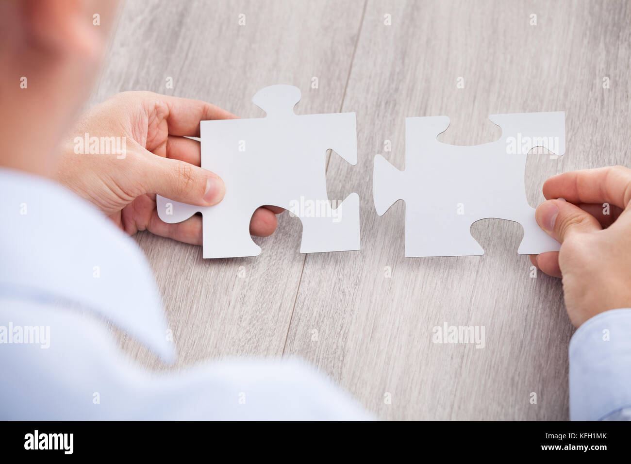 Cropped image of businessman joining jigsaw pieces at desk Stock Photo