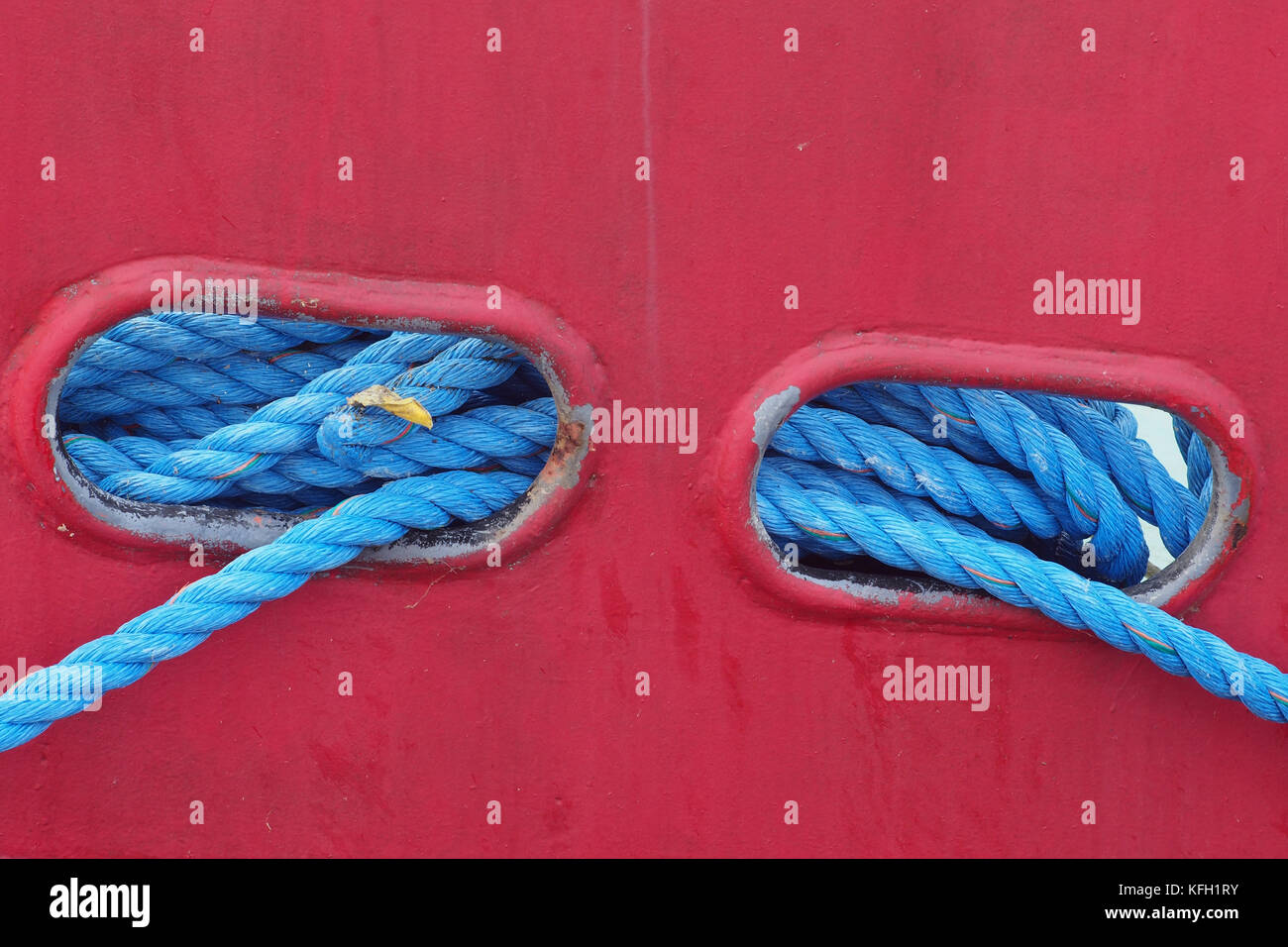 Blue mooring ropes through port holes on a fishing vessel, Scotland Stock Photo