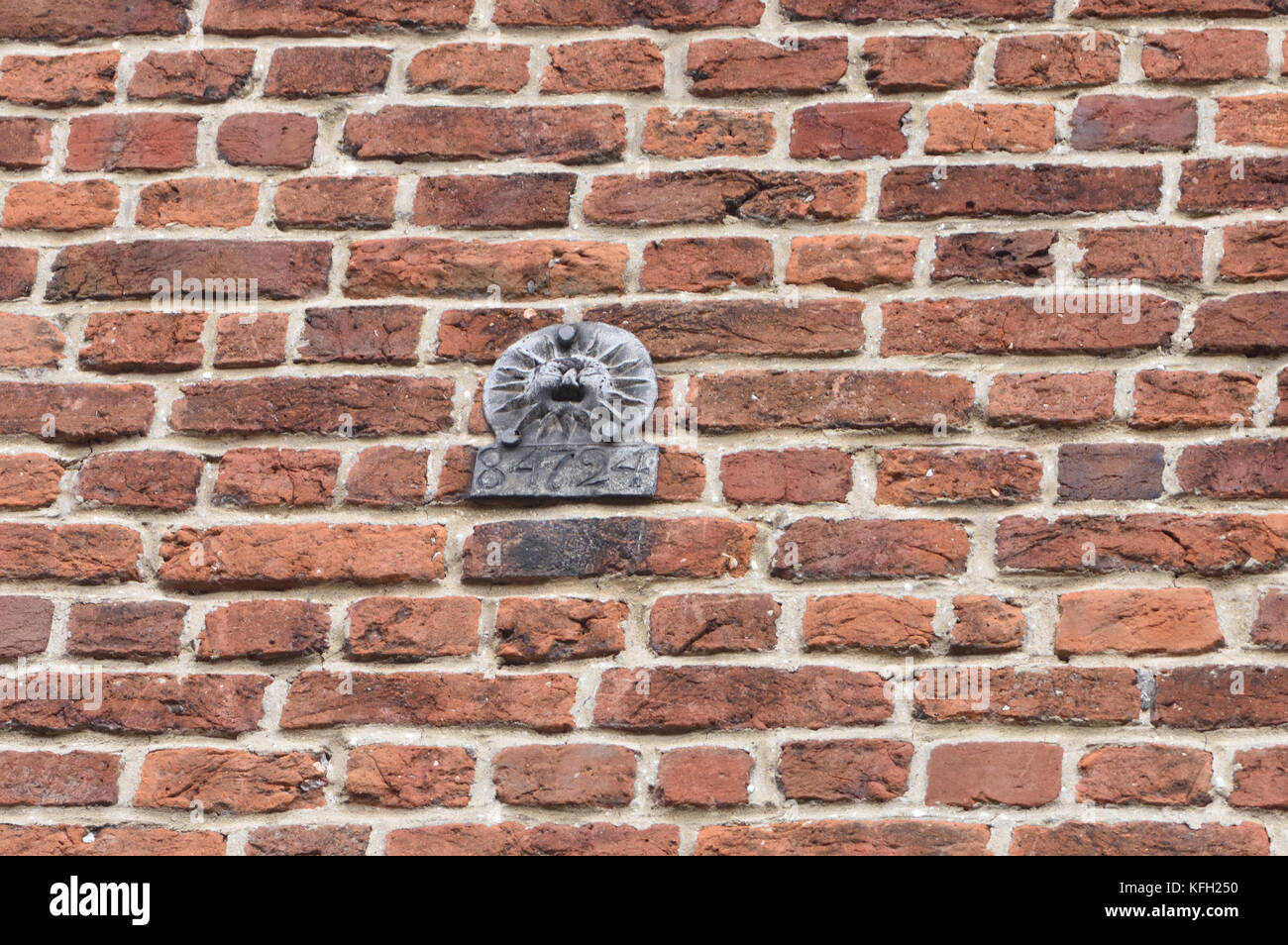A lead fire mark for the Sun Fire Office with a policy number stamped on it nailed to a brick wall. Winchester, Hampshire, UK. Stock Photo