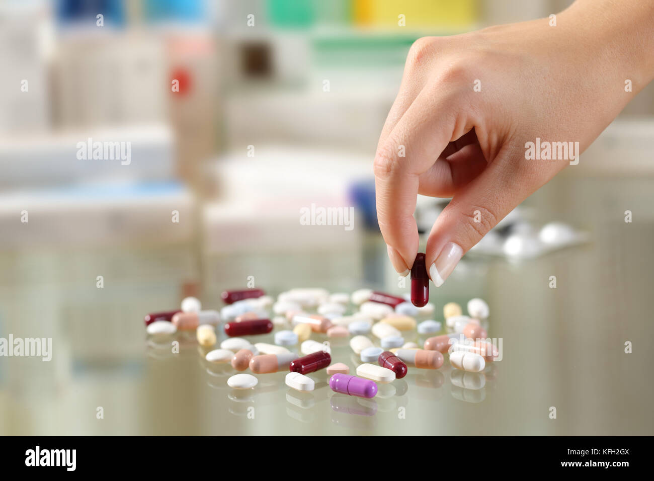 Close up of a woman hand catching a pill from a group of medicines on a glass table Stock Photo