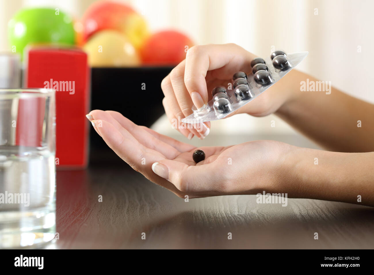 Close up of a woman hands getting a vitamin complex pill from a container Stock Photo