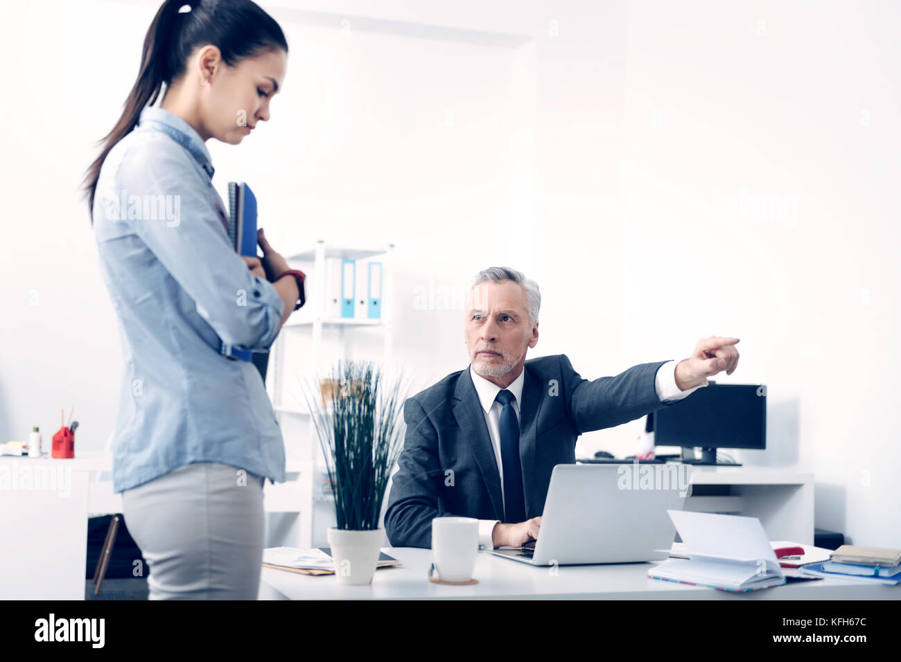 Serious mature businessman firing young office worker Stock Photo