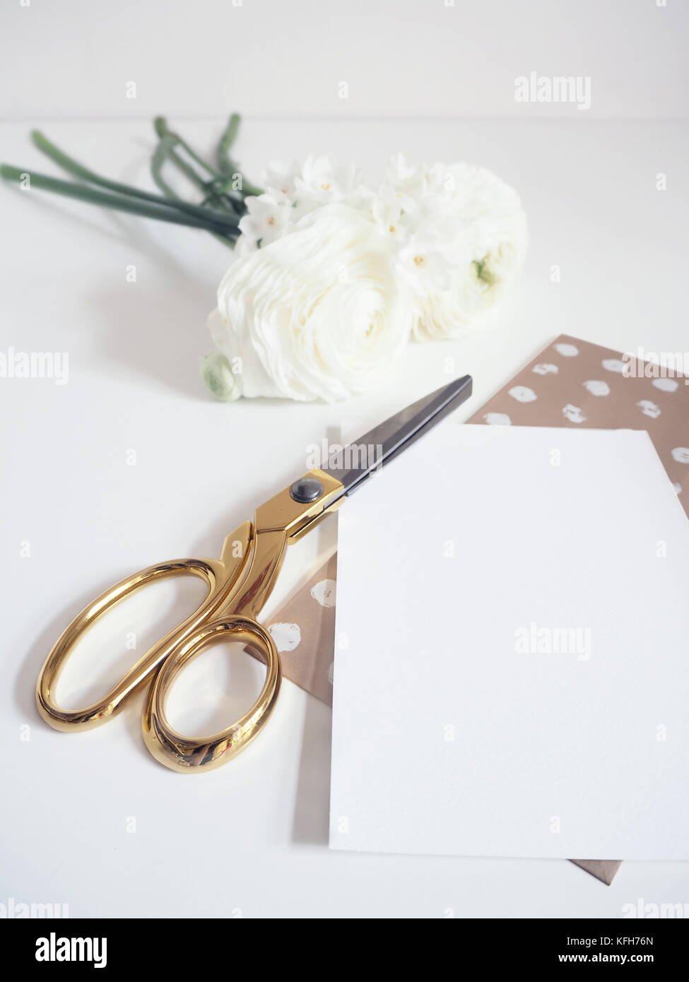 Styled stock photo. Feminine digital product mockup with buttercup and daffodil flowers, blank list of paper and golden scissors. White background. Flat lay, top view. Stock Photo