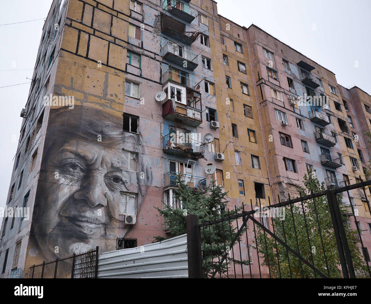 Avdijivka, Ukraine. 14th Oct, 2016. Babushka, a local teacher, is painted on the block of flats in Avdijivka, eastern Ukraine. Buildings here are heavy damaged by shelling. The painting was made by Australian street artist Guido van Helten.The conflict in the Donbass region of eastern Ukraine has been going on for more than 3 years and there is no sign of ending. The conflict was started in early 2014 as the aftermath of the 2014 Ukrainian revolution and the Euro maidan movement where the majority of Ukrainian in western Ukraine wanted to have closer relationship instead of with Russia wi Stock Photo