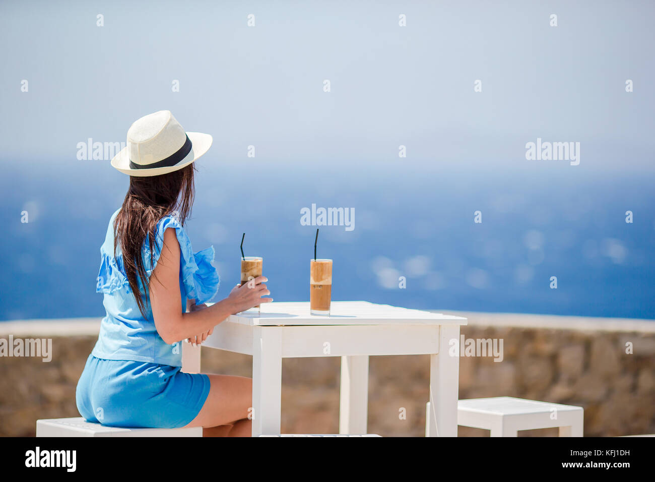 Young woman drinking cold coffee enjoying sea view. Stock Photo