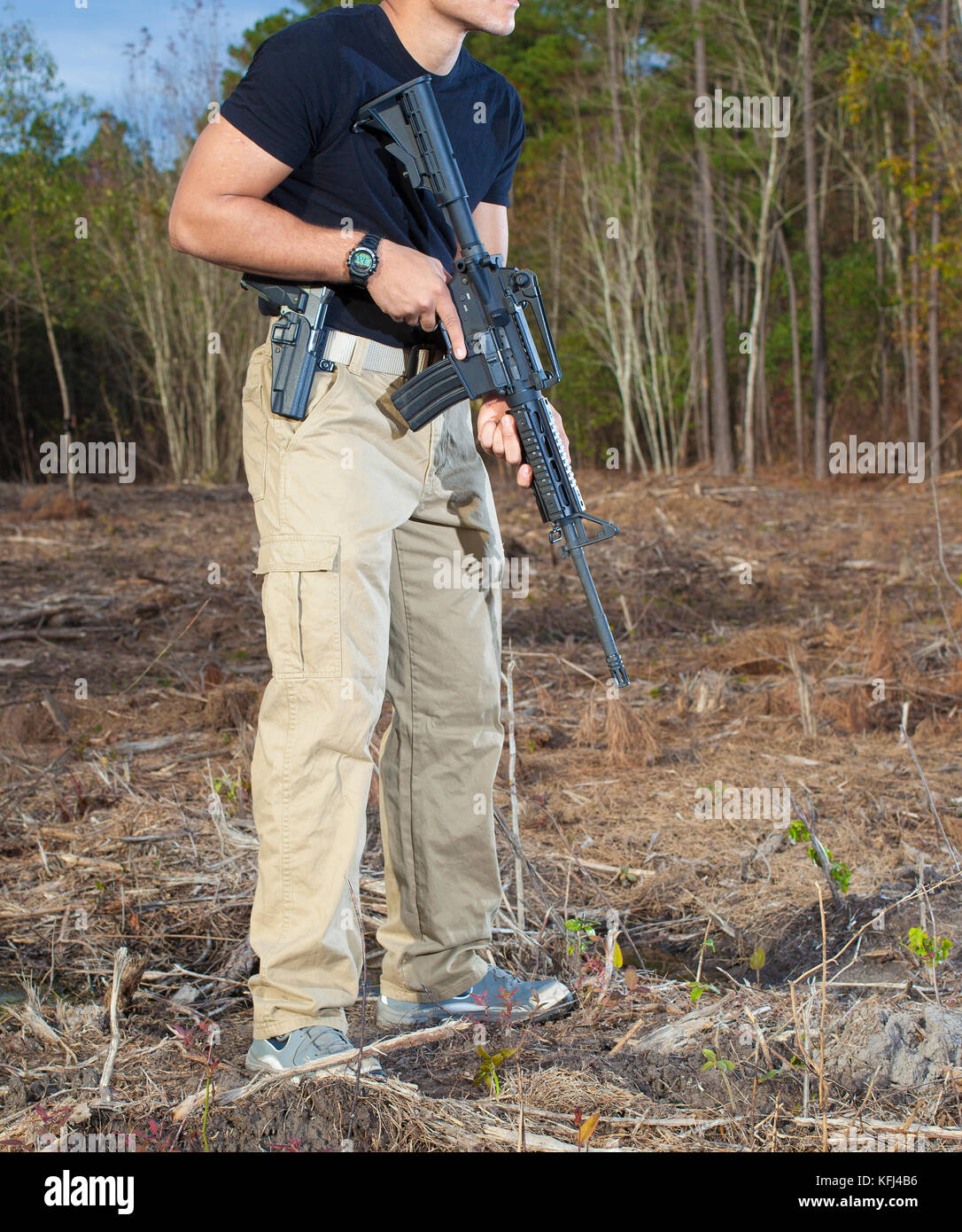Man with a semi automatic rifle and handgun in a field Stock Photo