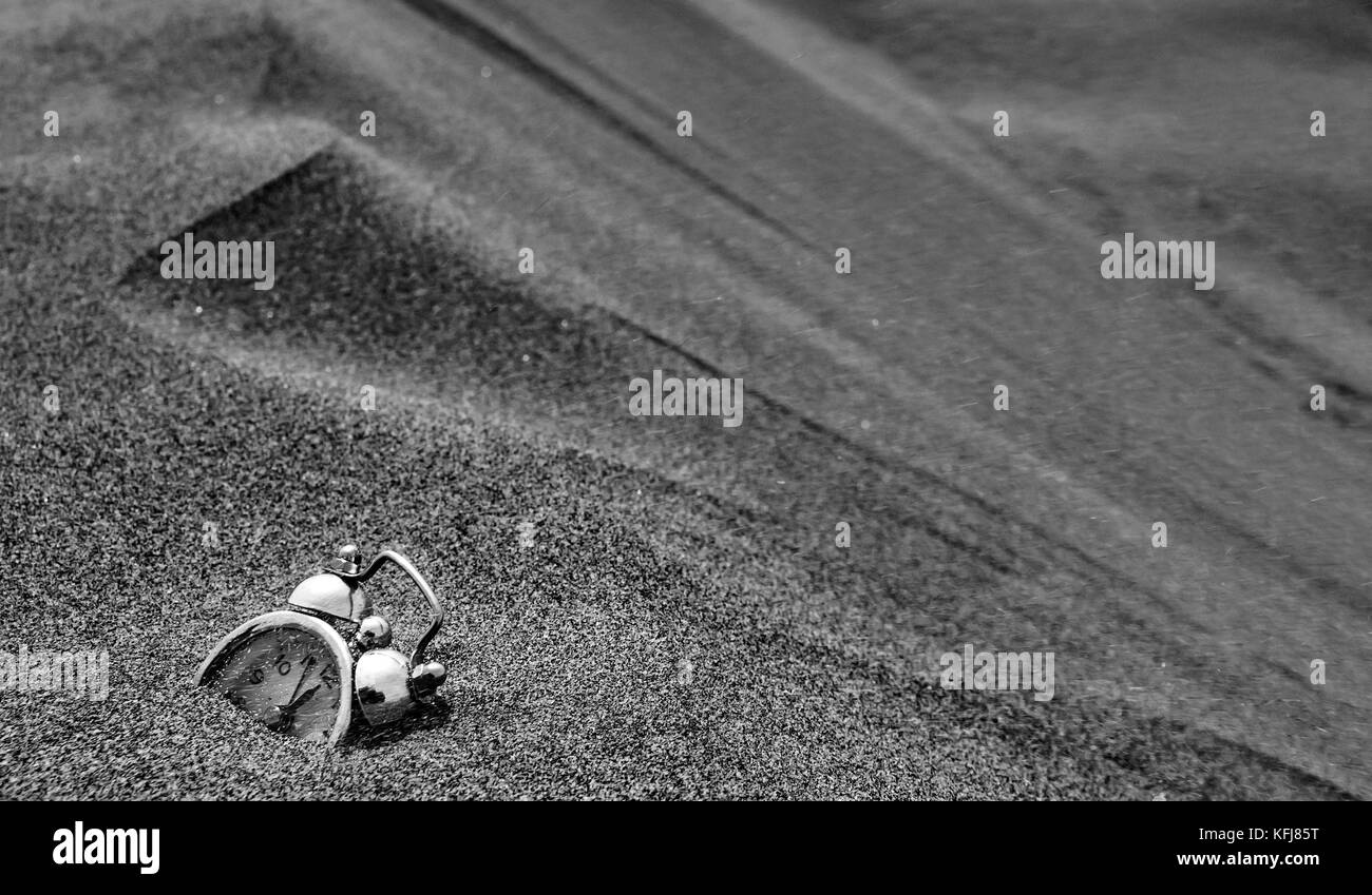 an abstract consept shot of a clock sinking in sand sorrounded by desert dunes meaning the passing of time Stock Photo