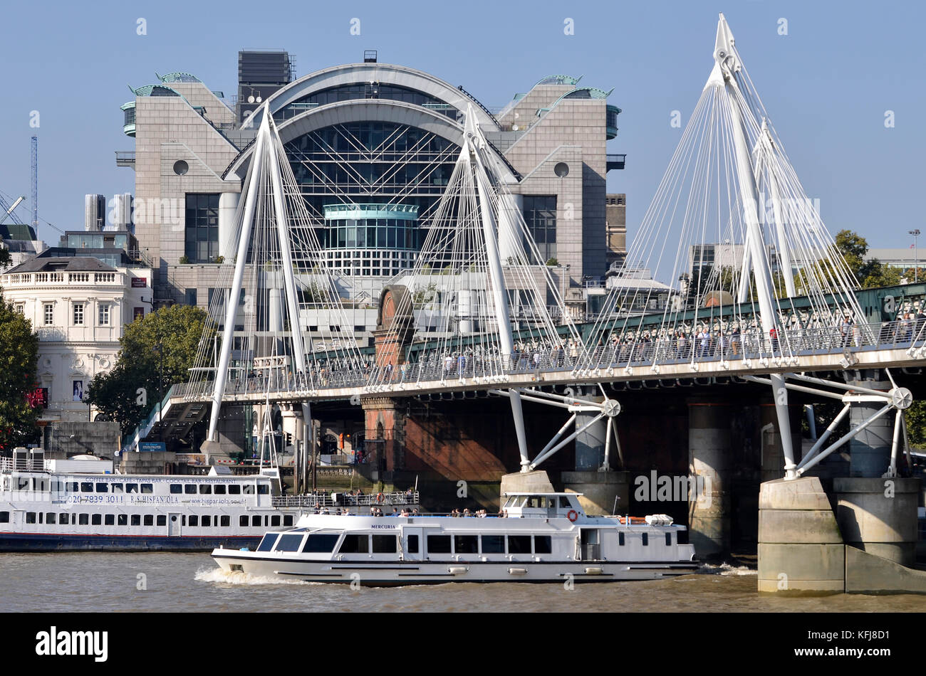 Golden Jubilee and Hungerford Bridges, River Thames, London, UK. Mercuria pleasure boat in foreground and Charing Cross Station behind. Stock Photo