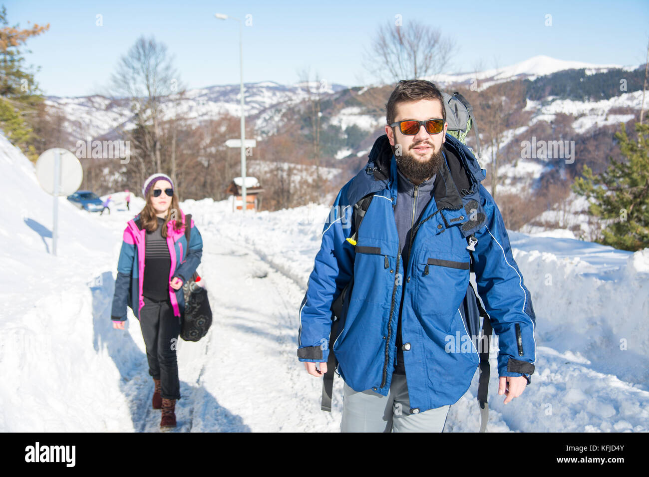 Couple of hikers exploring snowy mountain on a sunny day Stock Photo