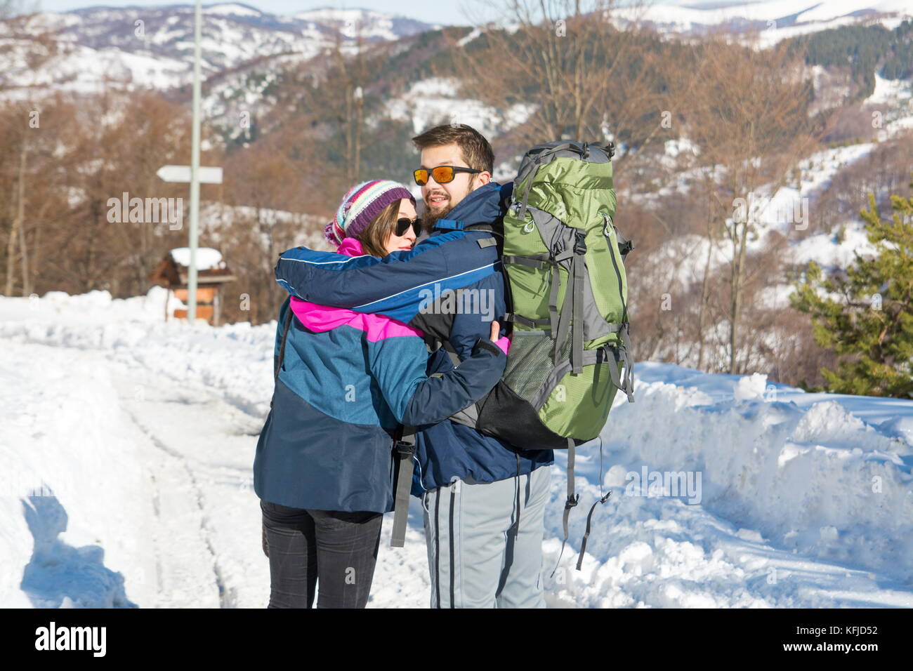 Couple of hikers exploring snowy mountain on a sunny day Stock Photo