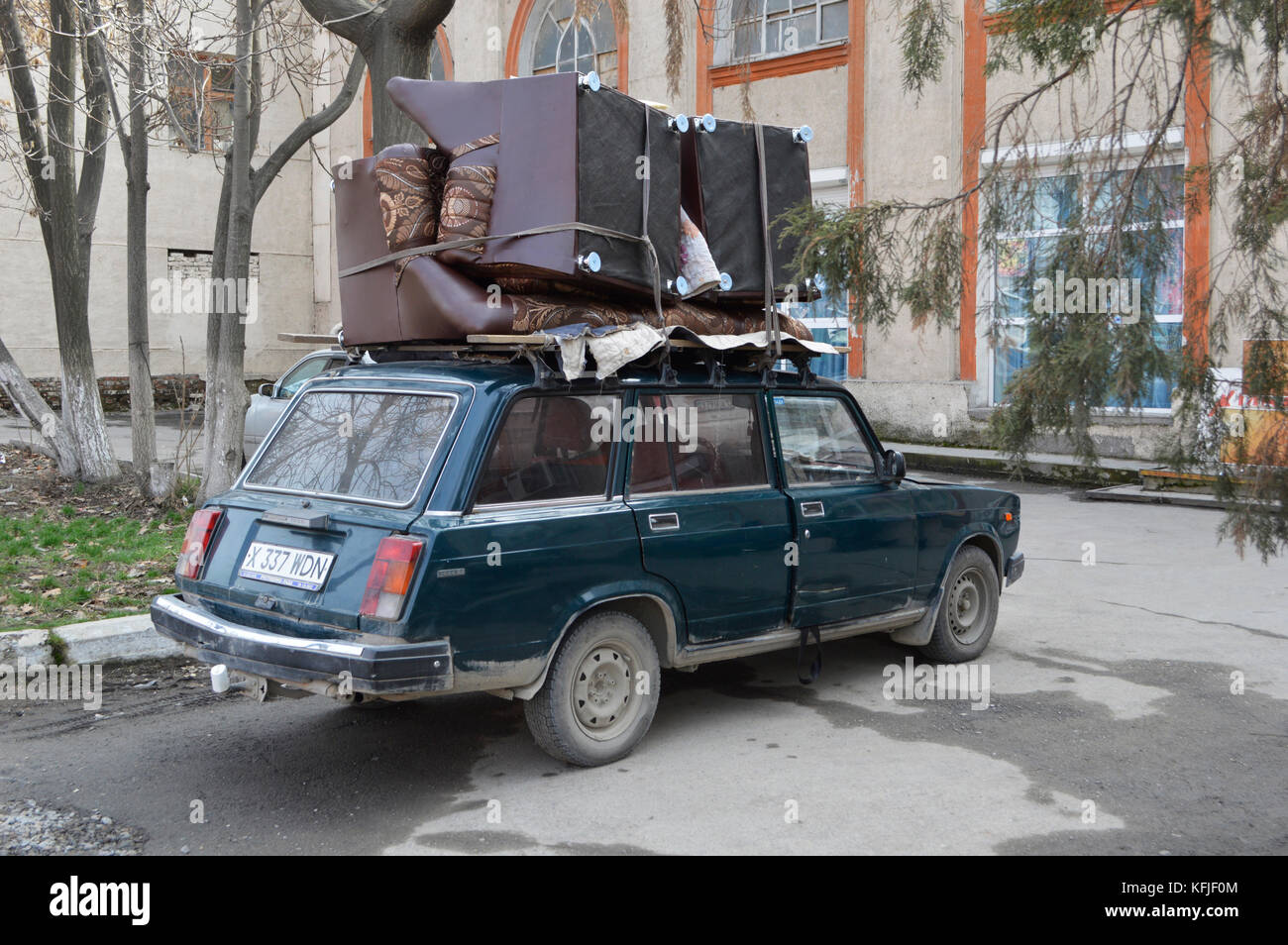 An overloaded family car that is trying to transport couch / sofa in  Kazachstan Stock Photo - Alamy