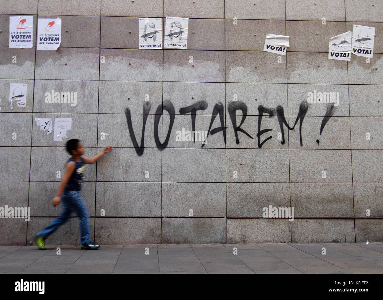 A boy walks in front of a graffiti that says we will vote , votarem in catalan. refers to the referendum of 1 October on the independence of the Catal Stock Photo