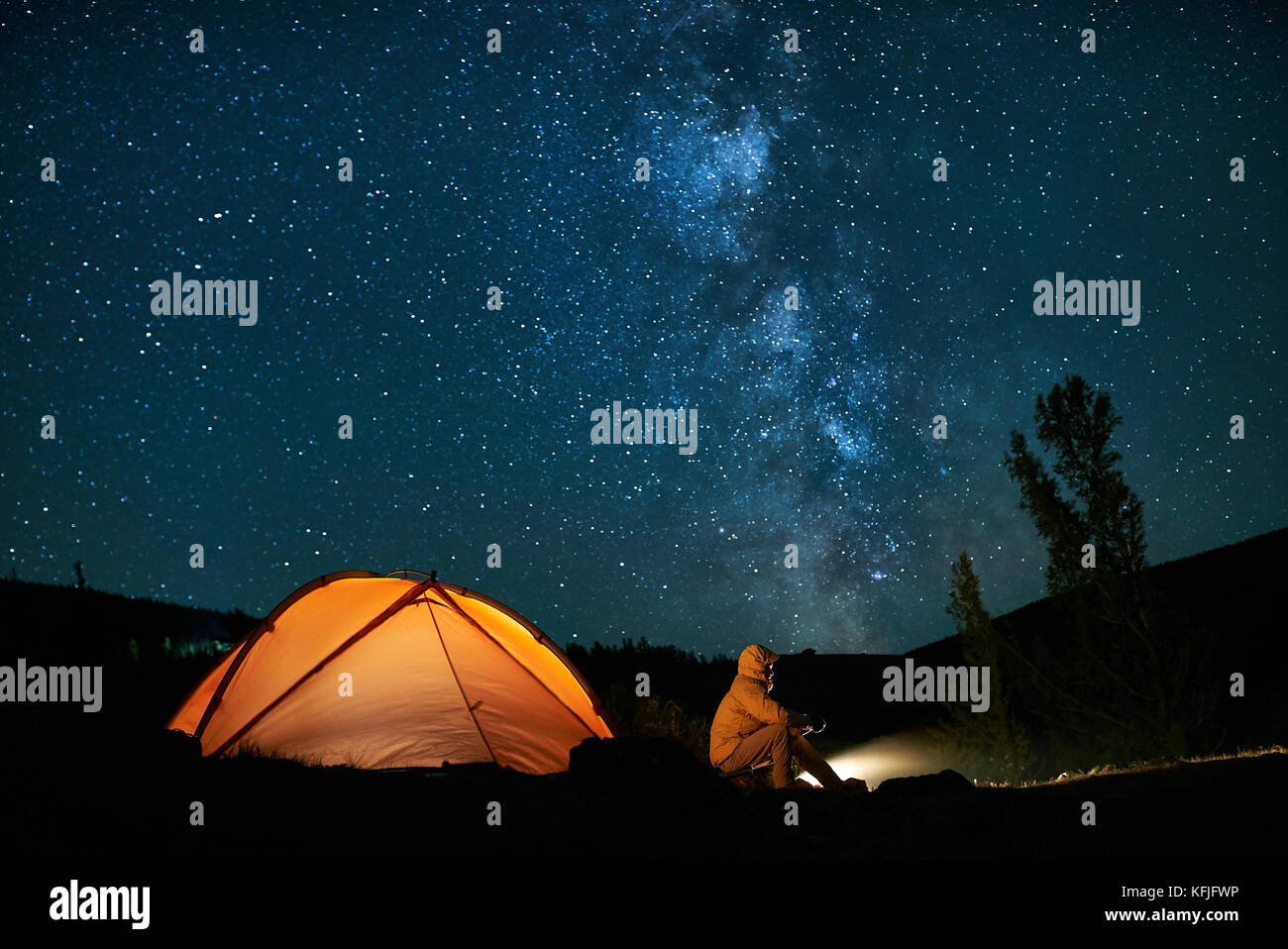 Man tourist near his camp tent at night. Stock Photo