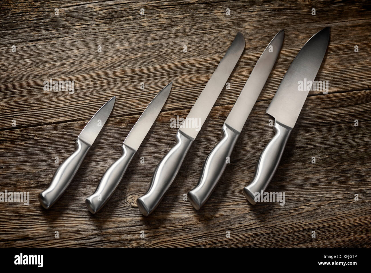 Metal kitchen knives set on rustic wood background Stock Photo