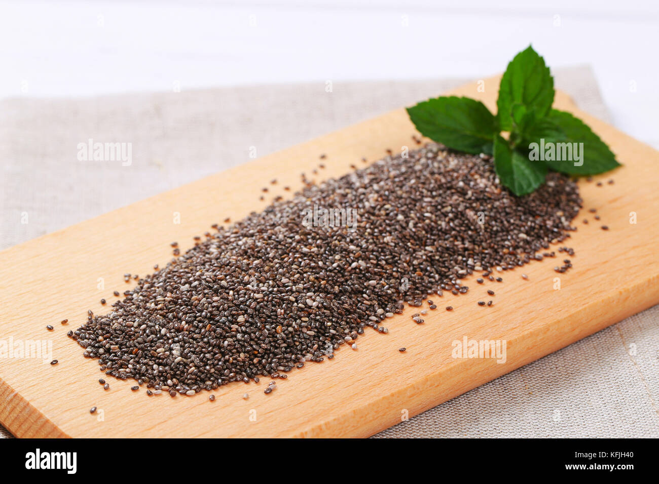 pile of chia seeds on wooden cutting board - close up Stock Photo