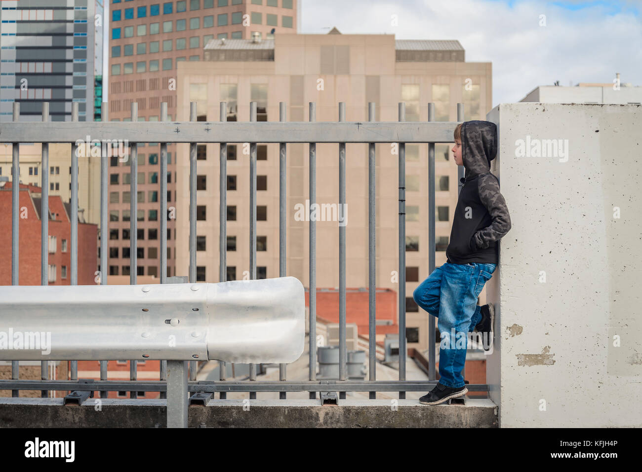 Lonely boy standing on top of the roof behind the fence Stock Photo