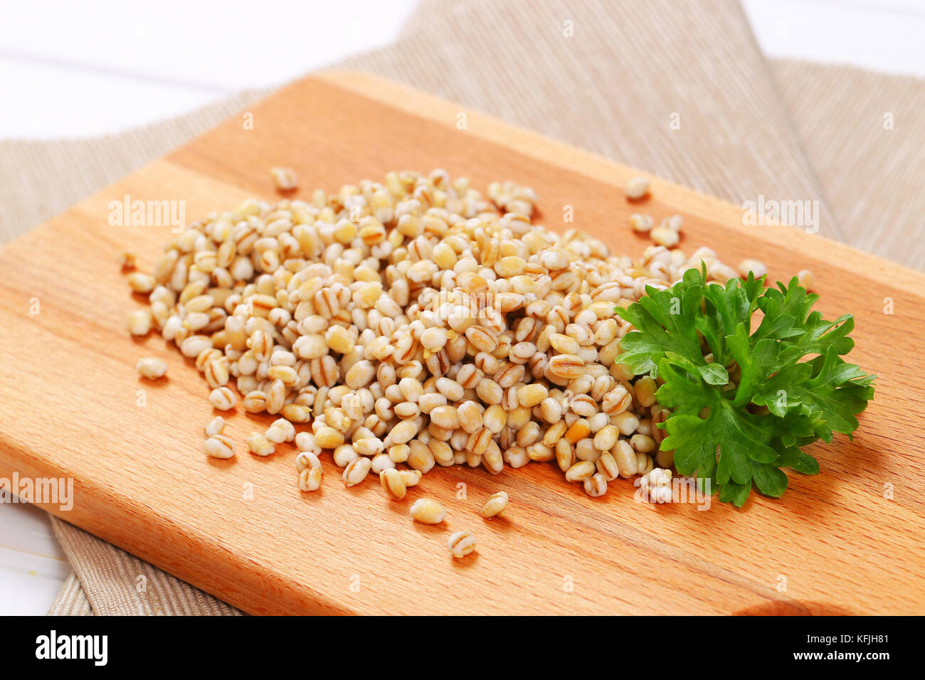 pile of cooked pearl barley on wooden cutting board - close up Stock Photo