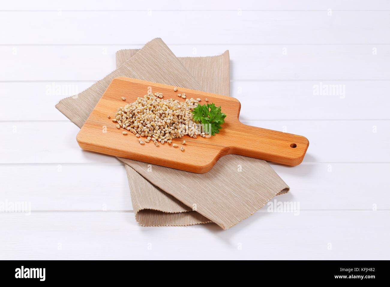 pile of cooked pearl barley on wooden cutting board Stock Photo