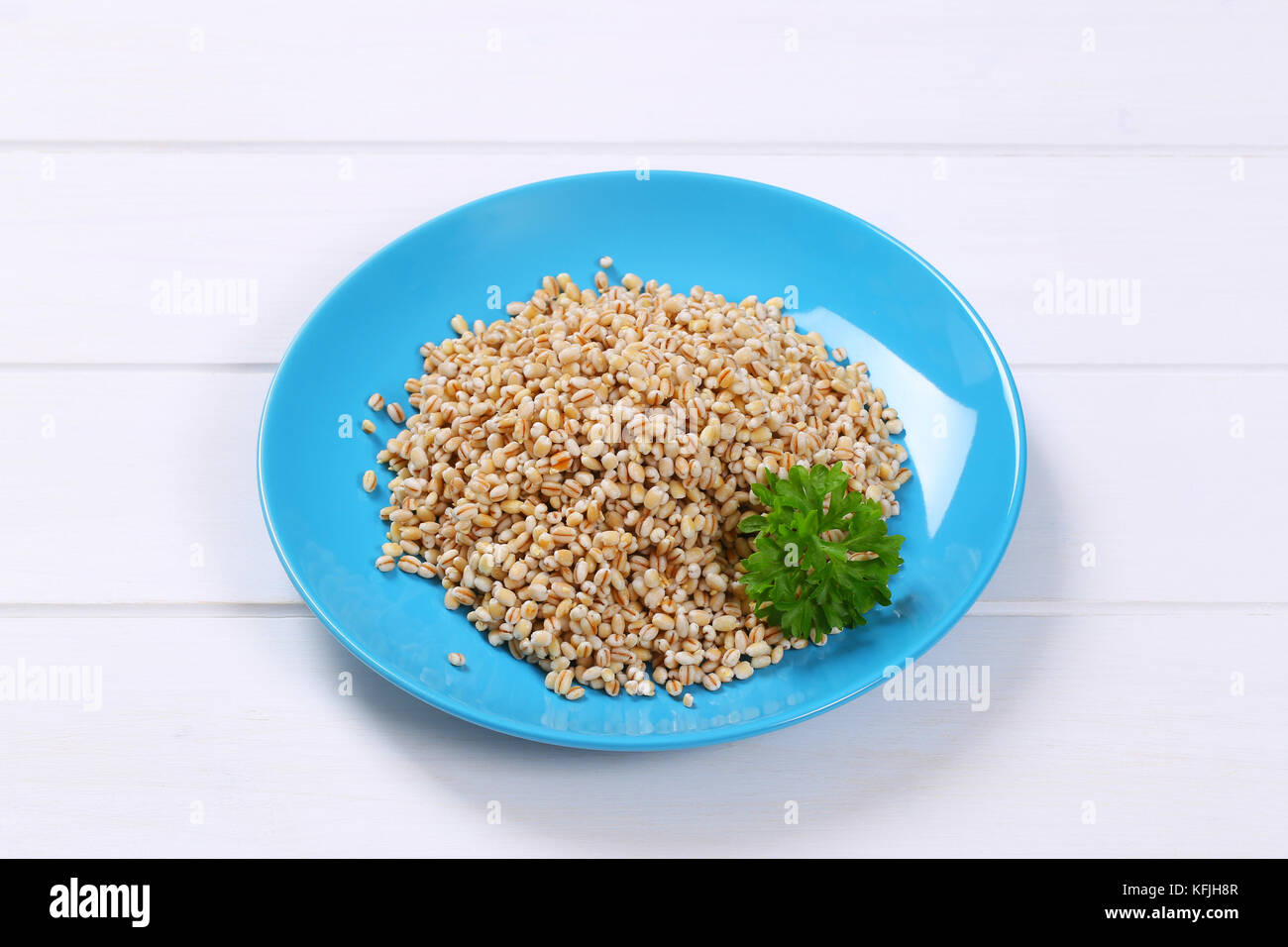 plate of cooked pearl barley on white wooden background Stock Photo