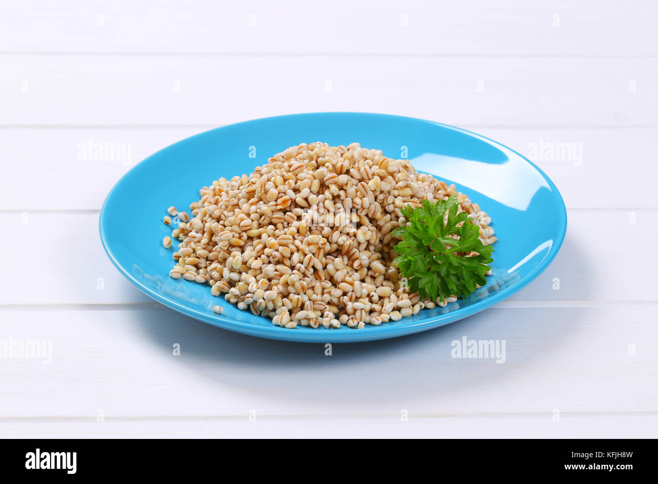 plate of cooked pearl barley on white wooden background Stock Photo