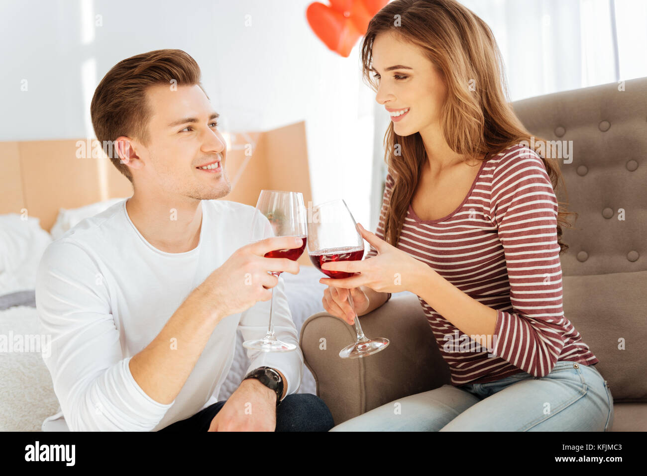 Beaming young couple drinking red wine at home Stock Photo - Alamy