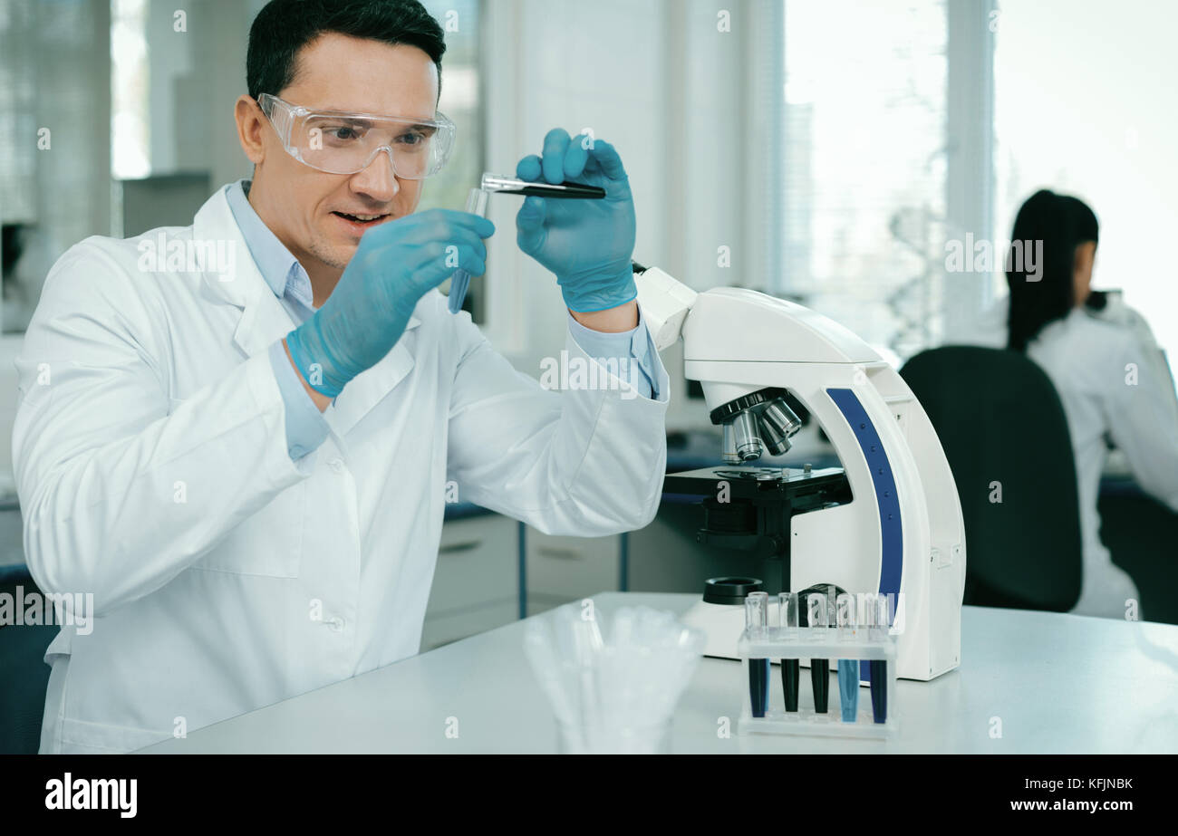 Enigmatical practitioner doing chemical experiment Stock Photo