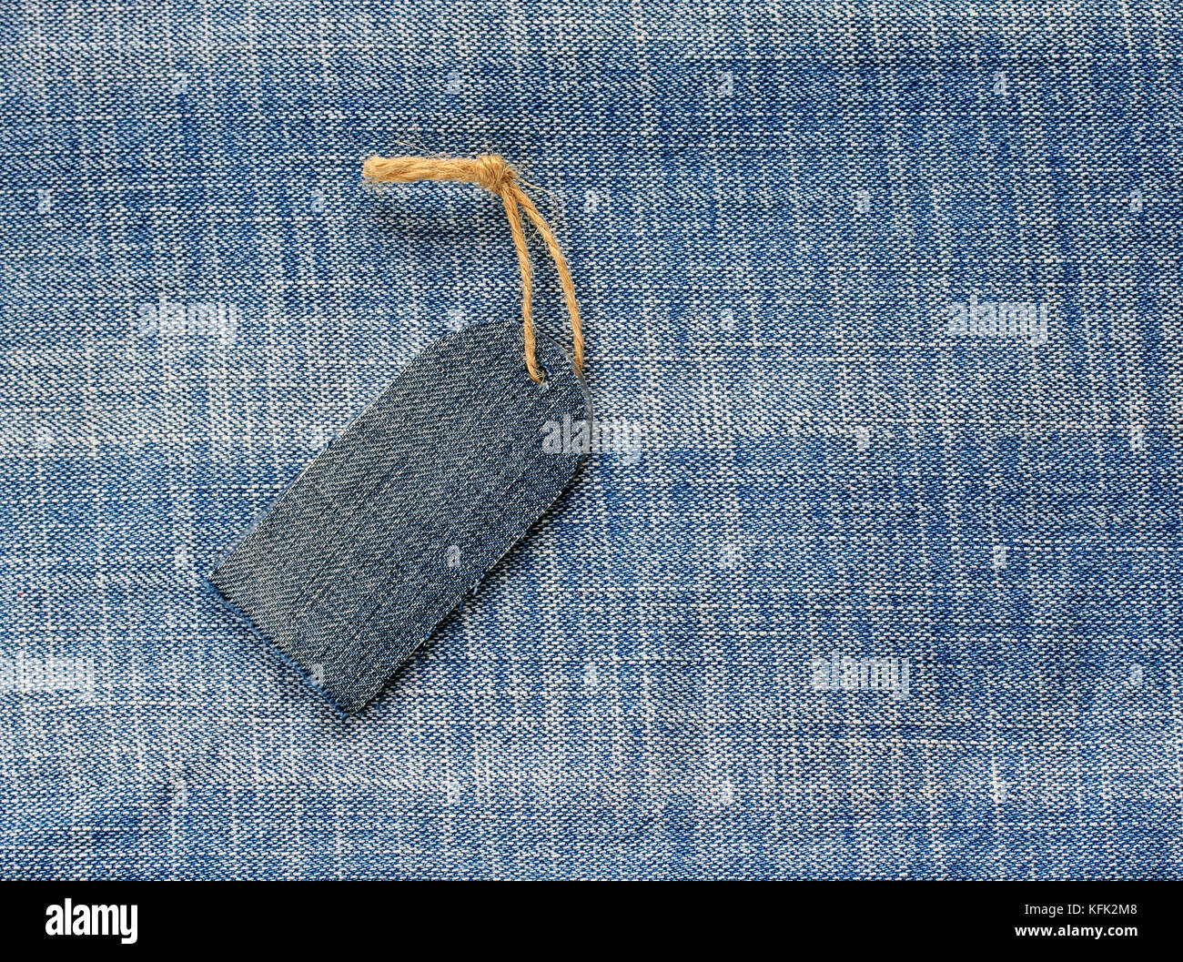 blank price tag on a rope on the background of denim for a seasonal