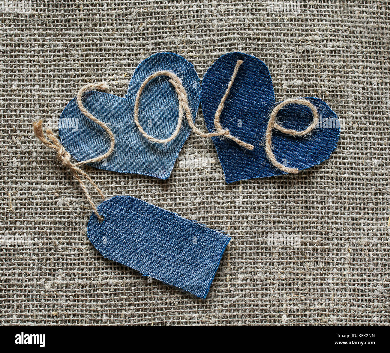 stylish inscription from sale of twine in my hand with a price tag of denim and serdarli on the background fabric burlap for window dressing Stock Photo