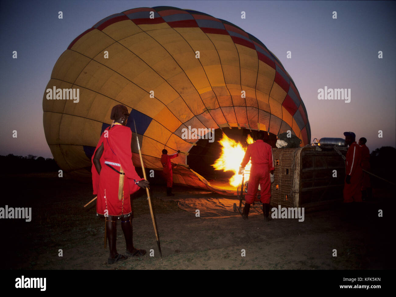 Masai tribesmen watching a hot air baloon take off, Masai Mara Game Reserve, Kenya Stock Photo