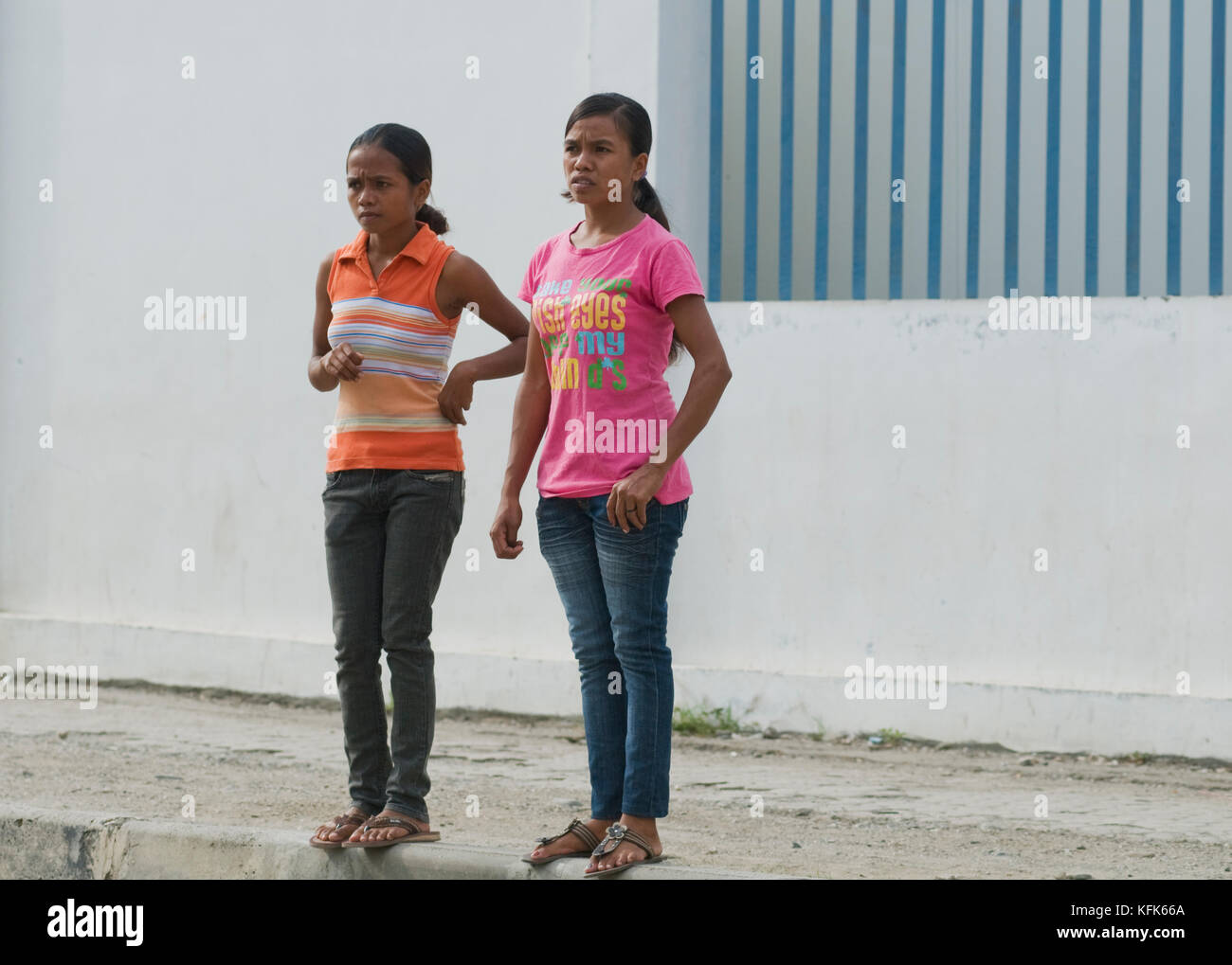 Two girls wait to cross a busy street in Dili, Timor-Leste (East Timor
