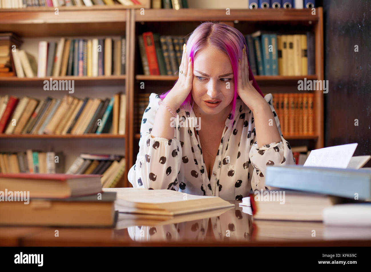 girl is preparing for the exam reads a lot of books in the library