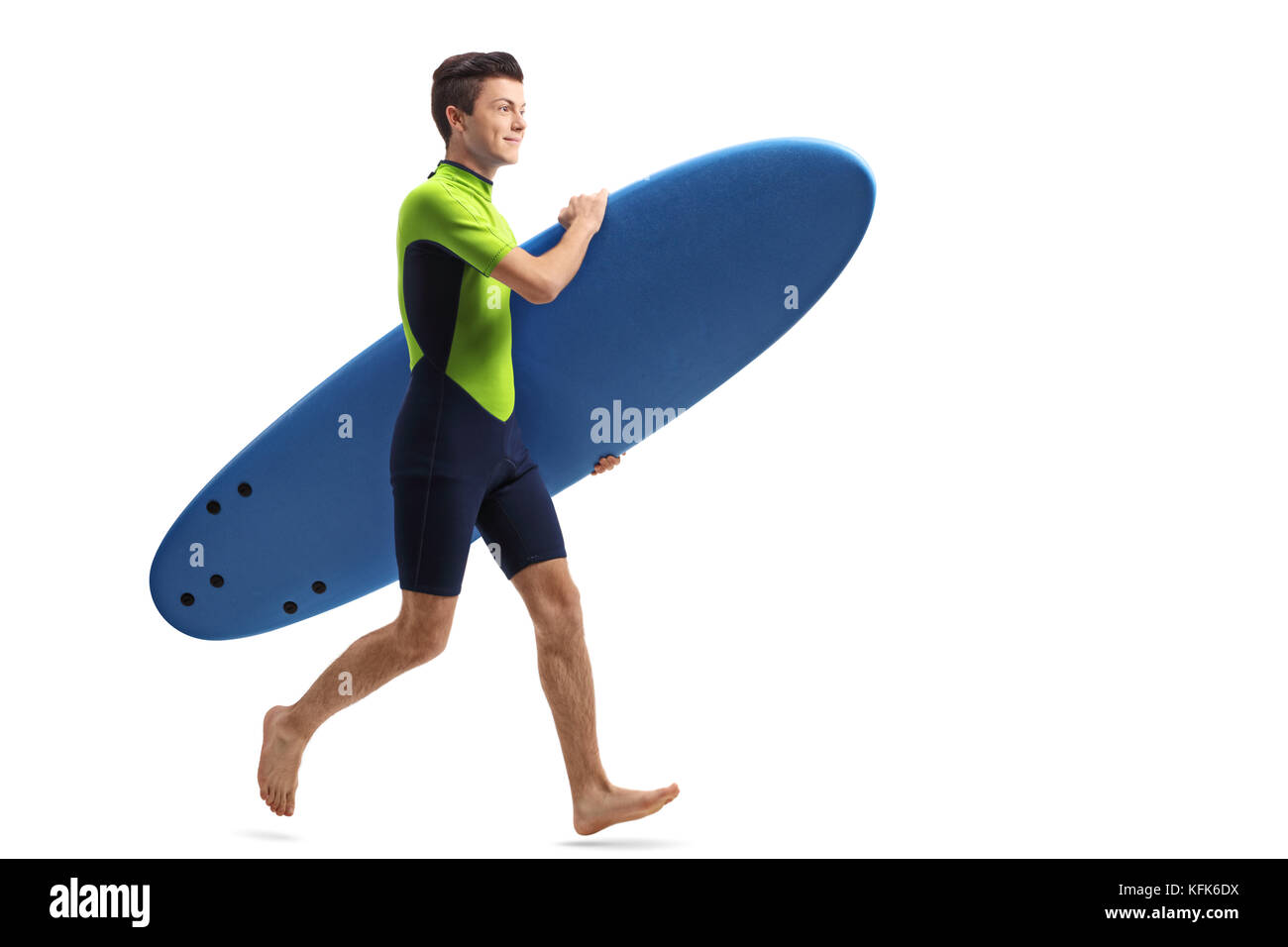 Full length profile shot of a teenage surfer with a surfboard running isolated on white background Stock Photo