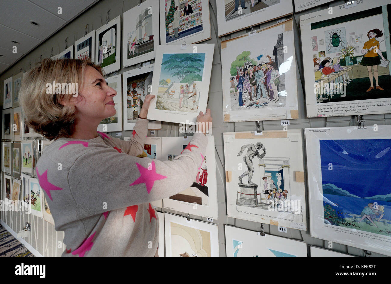 Auctioneer Catherine Southon holds examples from the Smilby cartoon collection, including works that appeared in Playboy, as she sets up her sale room in Farleigh, Surrey, ahead of their auction on the 1st of November. Stock Photo