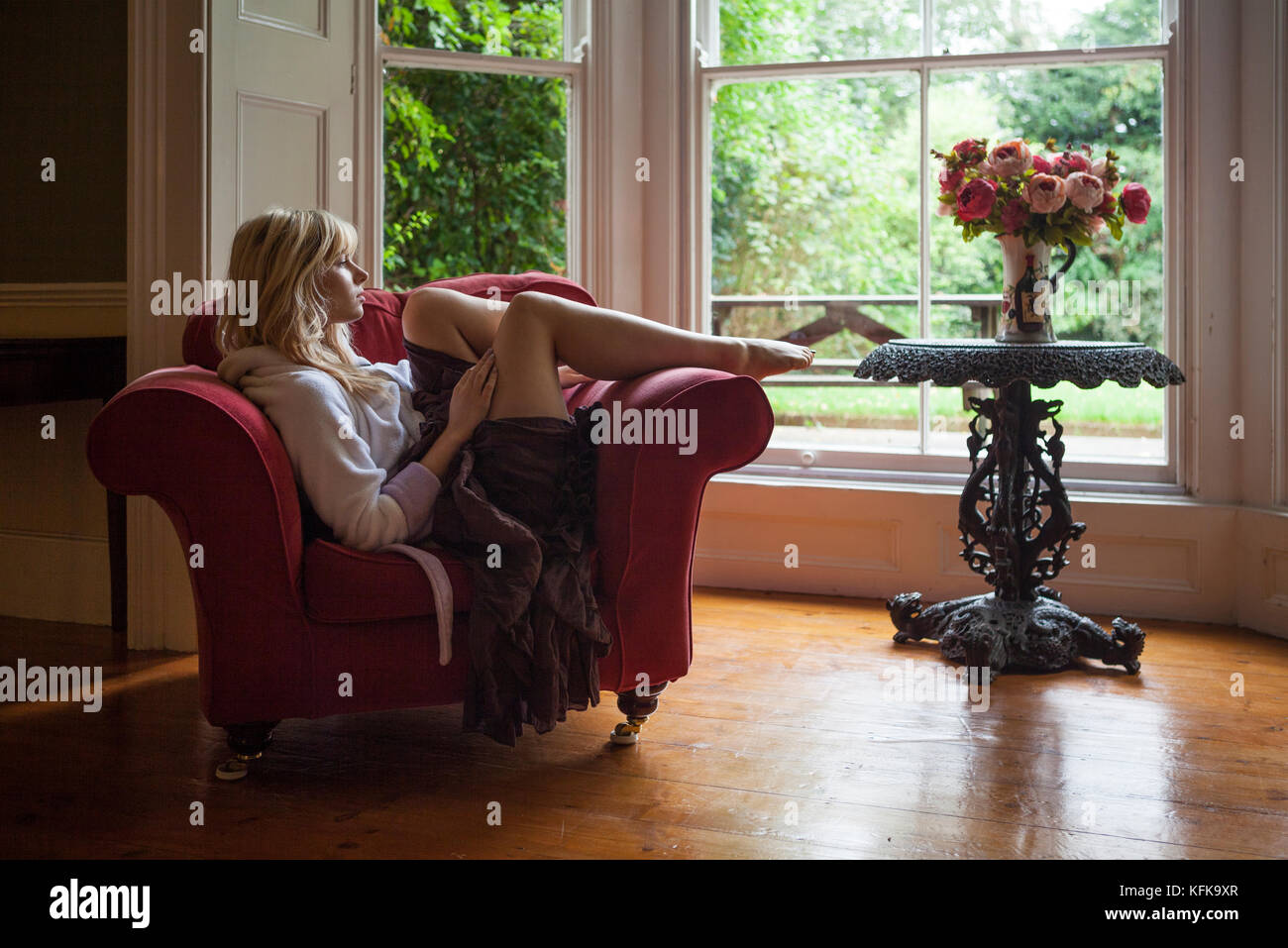 Thinking of You, Girl Relaxing in a Chair looking out of a Bay Window Stock Photo