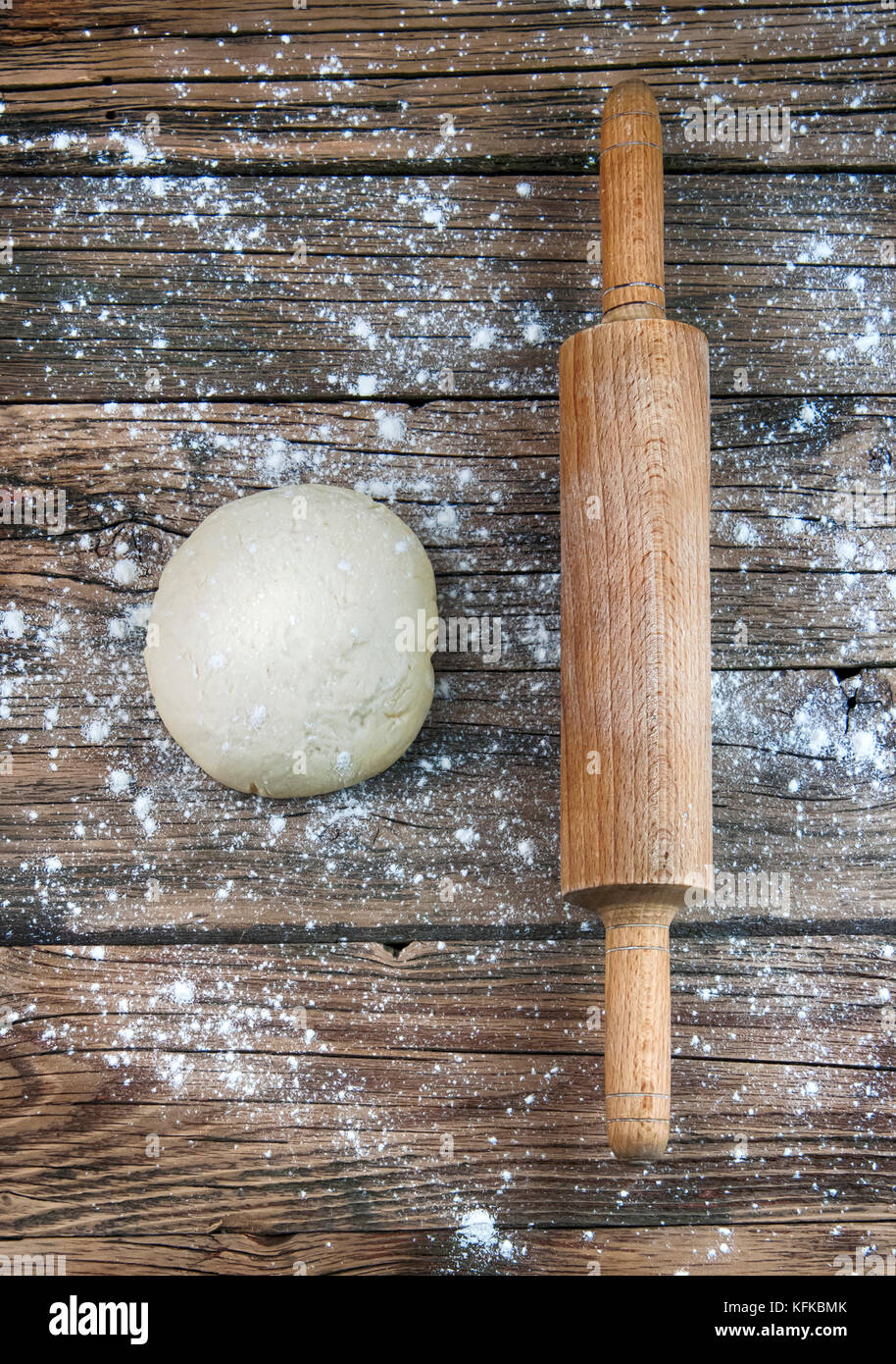 ball of pizza dough on a rustic wooden background with dusting of flour