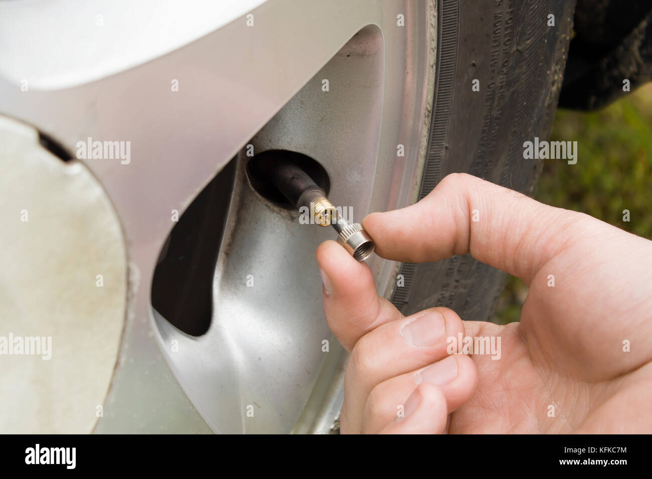 Mechanic's hand unscrews the valve in the wheel of the car. Stock Photo