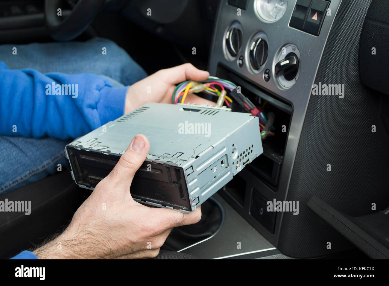 The hands of the car electrician connect the cube cords of the cables from the radio to the car's electrical system. The car electrician connects Stock Photo