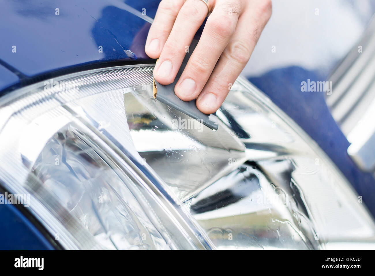 The car mechanic's hand polishes with sandpaper and water frosted reflector glass. Refinish the headlights. Polished matt glass headlight with sa Stock Photo