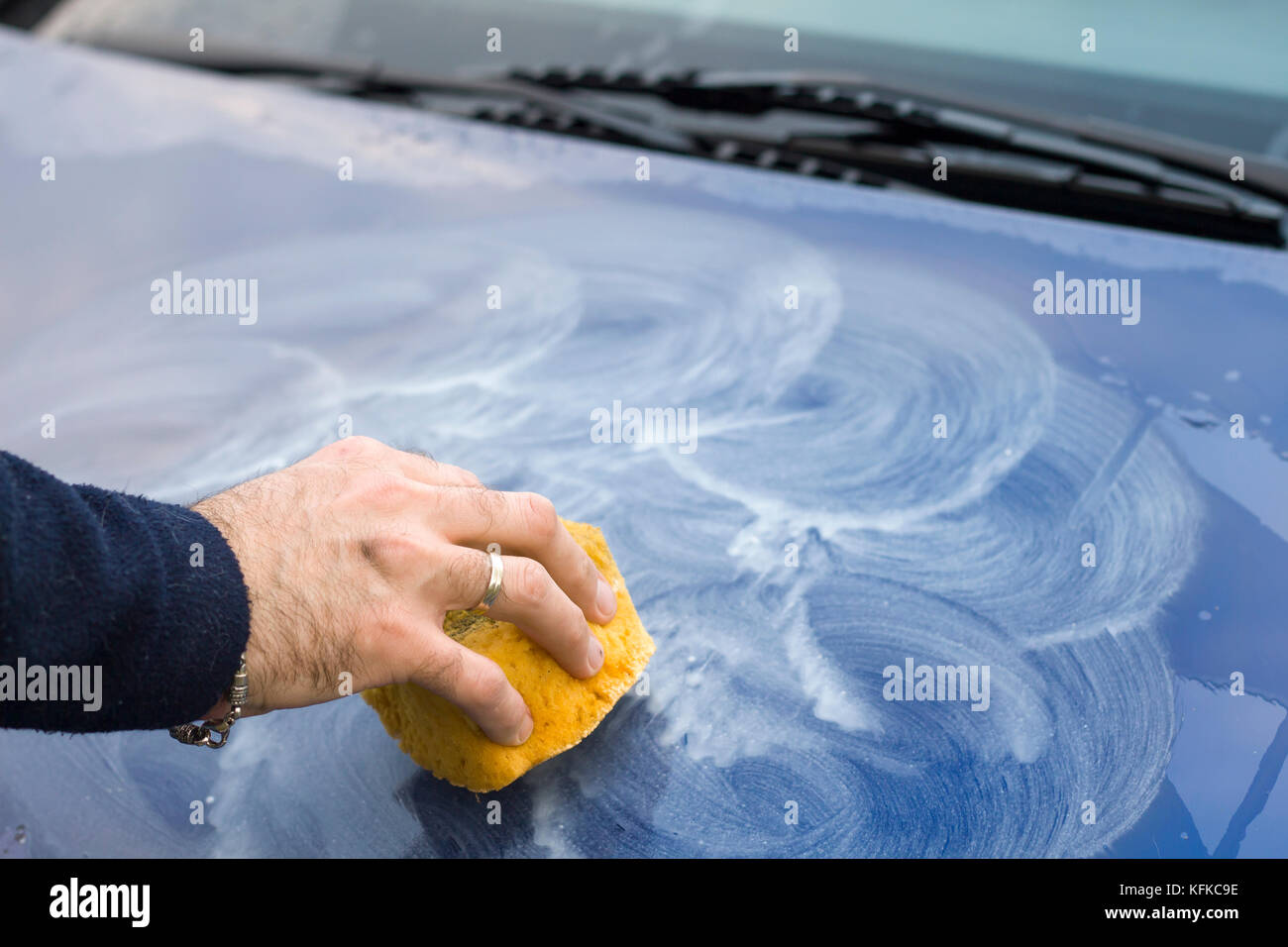 . Apply polishing paste to the car with a sponge. Male hand
