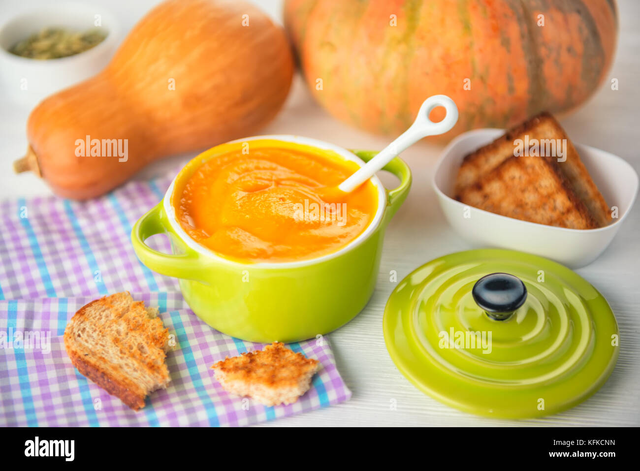 creamy pumpkin soup and bread in green bowl on napkin, concept of healthy eating Stock Photo