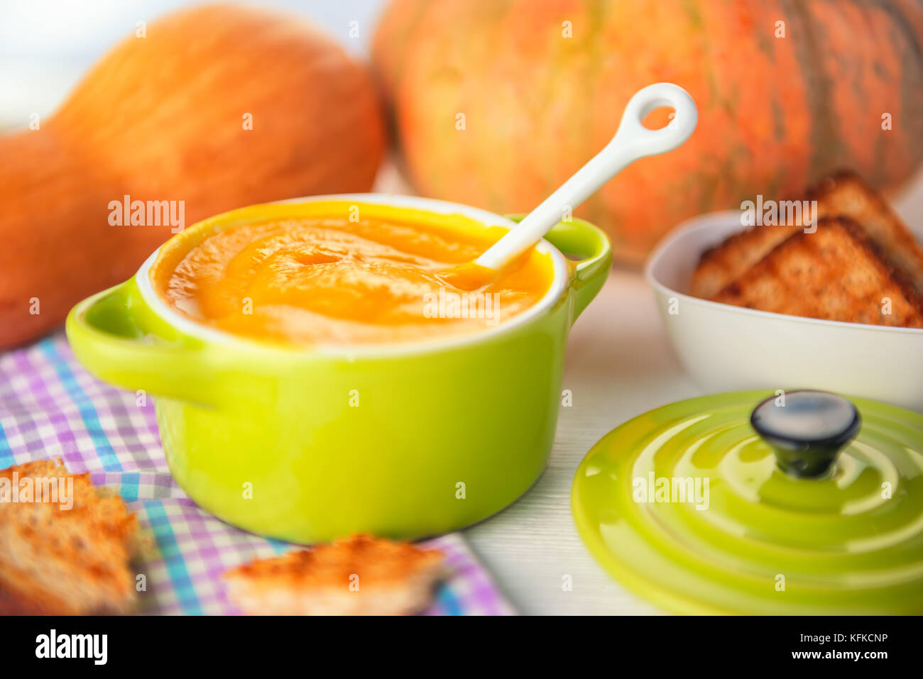 homemade creamy pumpkin soup and bread in green bowl on napkin, concept of Thanksgiving Stock Photo
