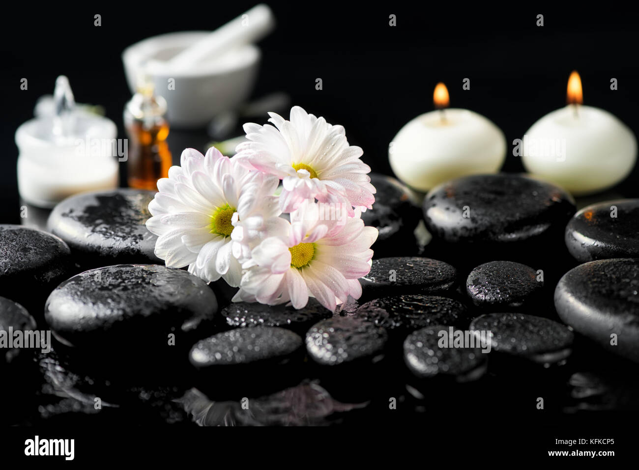 spa concept of white daisy flowers, candles, fragrance oil and zen