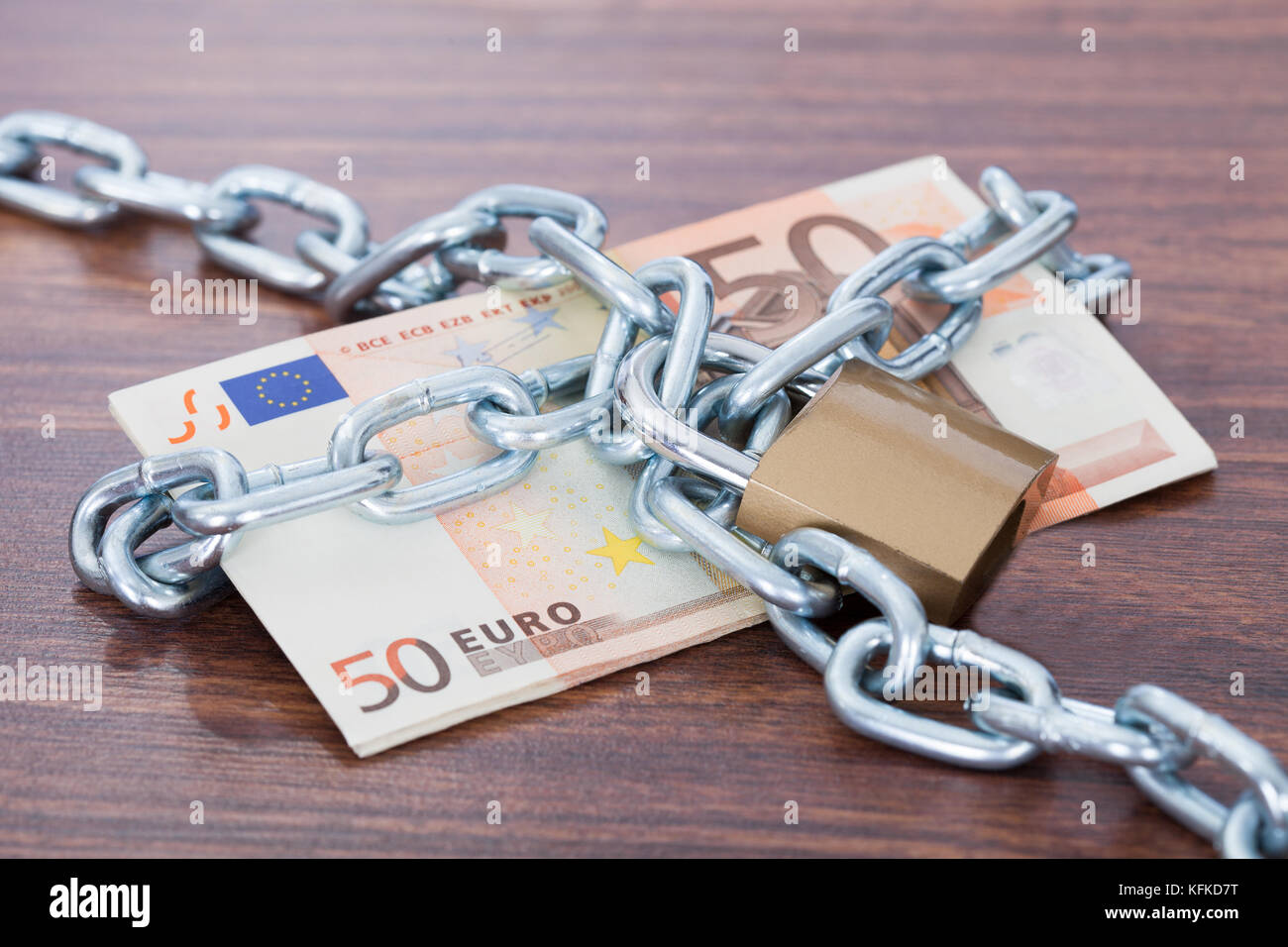 Fifty euro notes with chain and padlock on table Stock Photo