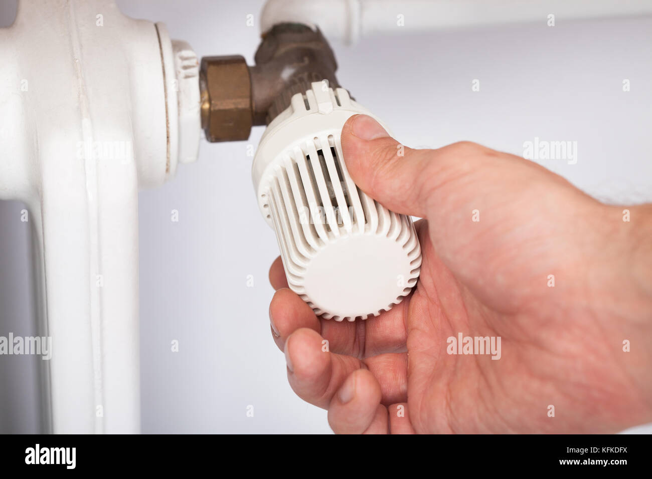 Closeup of man adjusting temperature on radiator thermostat Stock Photo