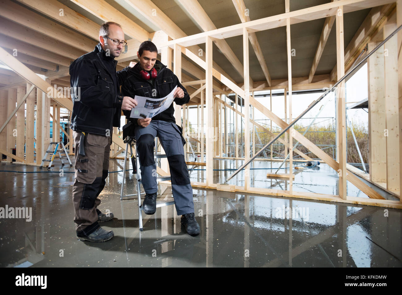 Carpenters Analyzing Plan At Construction Site Stock Photo