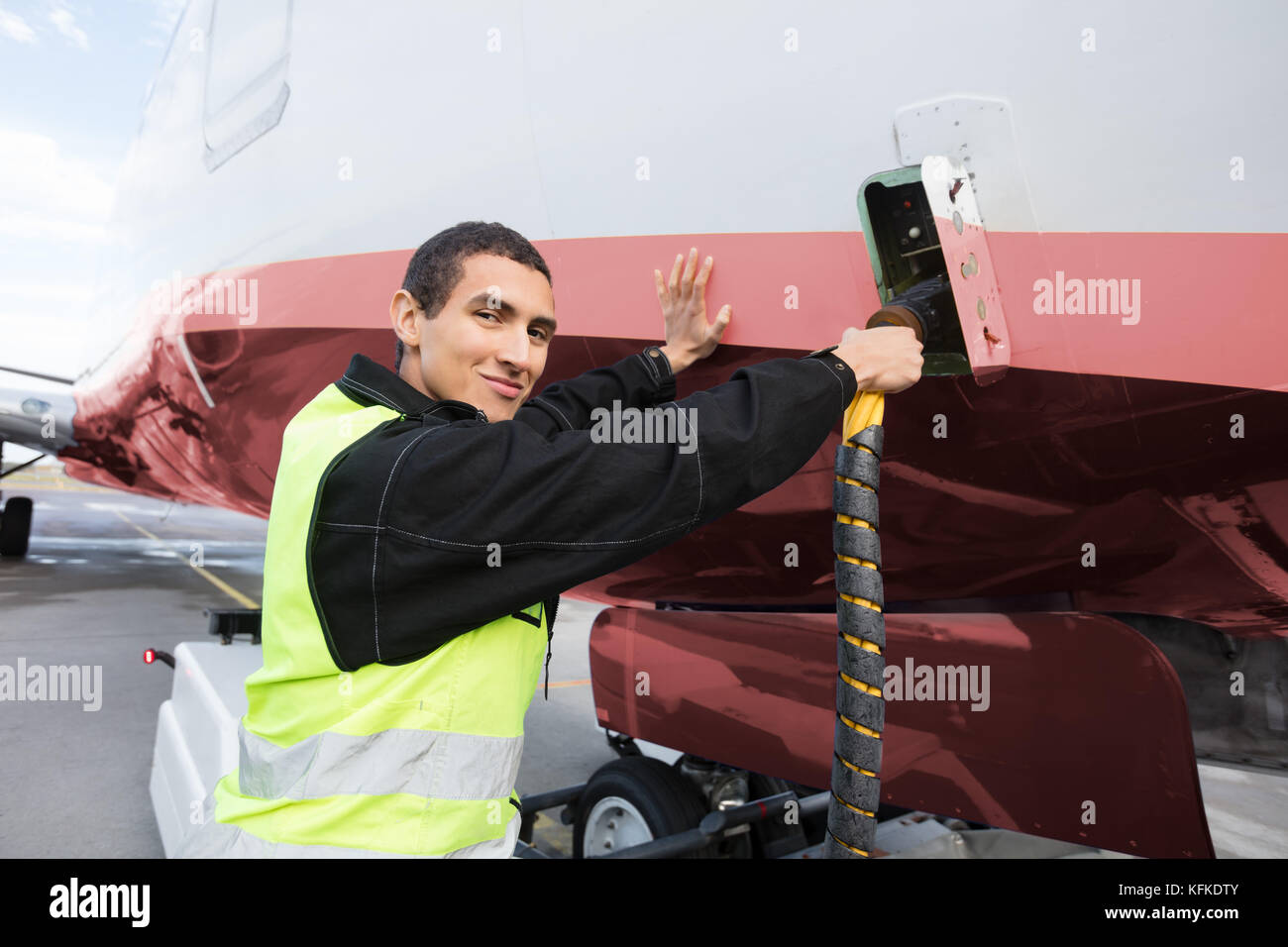 Portrait Of Crew Member Charging Airplane On Runway Stock Photo