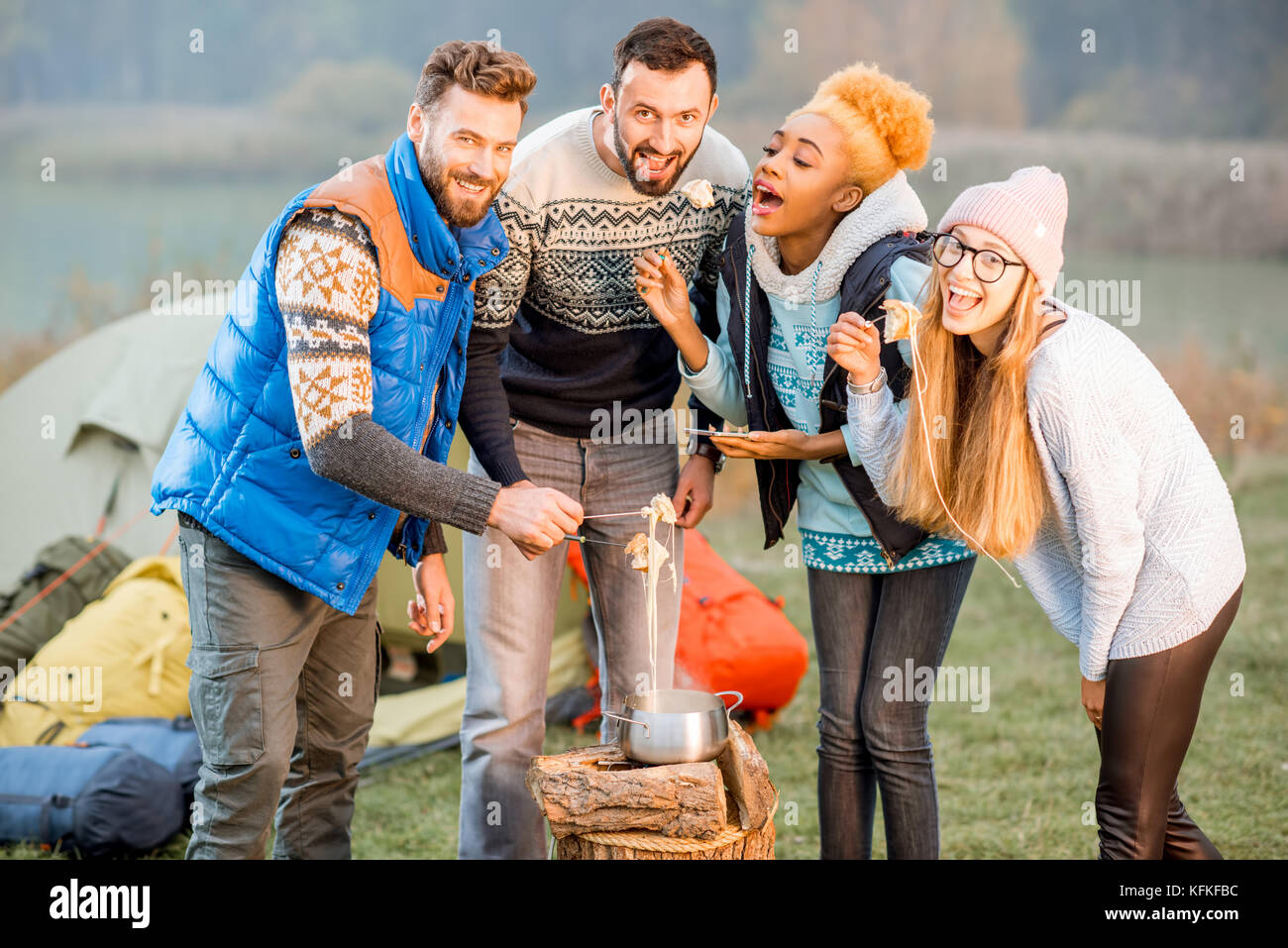 Friends in sweaters eating fondue outdoors Stock Photo
